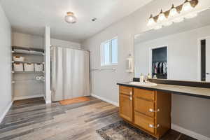 Bathroom featuring baseboards, visible vents, a shower with shower curtain, wood finished floors, and vanity