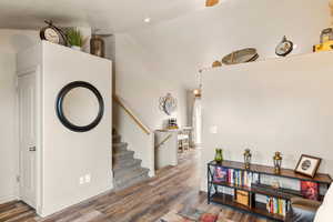 Interior space with lofted ceiling, stairway, and wood finished floors