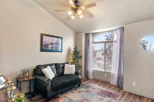 Living area with lofted ceiling, wood finished floors, a ceiling fan, and baseboards