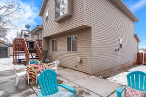 Snow covered house with outdoor dining area, stairway, a patio area, and fence