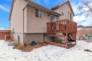 Snow covered property featuring stairs, a deck, and fence