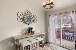 Dining space featuring lofted ceiling, light wood-style floors, baseboards, and an inviting chandelier