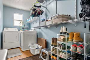 Laundry room with laundry area, visible vents, wood finished floors, independent washer and dryer, and a textured ceiling