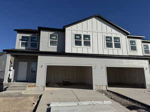 View of front of property with board and batten siding, driveway, and a garage