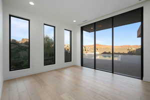 Empty room featuring light wood-style floors, a wealth of natural light, a mountain view, and recessed lighting