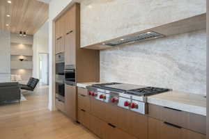 Kitchen featuring light wood-style flooring, open floor plan, light countertops, appliances with stainless steel finishes, and decorative backsplash