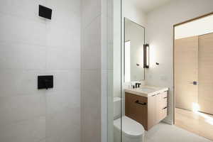 Bathroom with tiled shower, vanity, and toilet