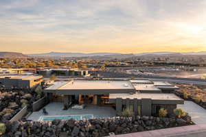 Back of house at dusk with a patio area, fence, and a mountain view