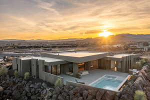 Rear view of property with stucco siding, a patio area, a mountain view, and an in ground hot tub