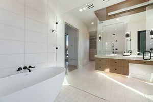 Full bath with tile walls, a soaking tub, visible vents, vanity, and tile patterned flooring