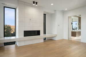 Unfurnished living room featuring light wood-style flooring, recessed lighting, visible vents, baseboards, and a tiled fireplace