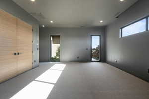 Carpeted empty room featuring visible vents and recessed lighting