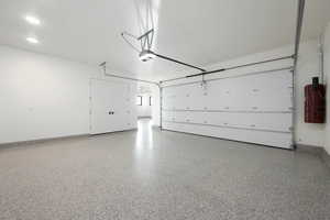 Garage featuring a garage door opener, recessed lighting, and baseboards