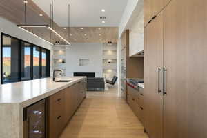 Kitchen with a large island, modern cabinets, wine cooler, open floor plan, and a sink