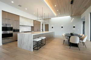 Kitchen featuring light countertops, modern cabinets, visible vents, and decorative light fixtures