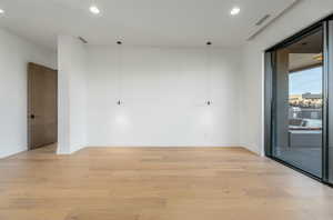 Empty room with light wood-style floors, recessed lighting, visible vents, and baseboards