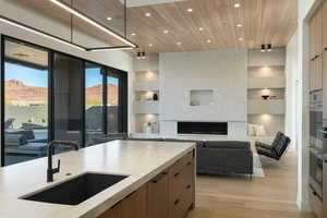 Kitchen featuring a premium fireplace, a sink, open floor plan, light countertops, and modern cabinets