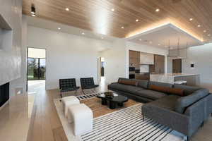 Living area featuring recessed lighting, a fireplace, a towering ceiling, wood ceiling, and light wood finished floors