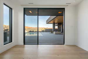 Interior space with visible vents, a mountain view, light wood-style flooring, and baseboards