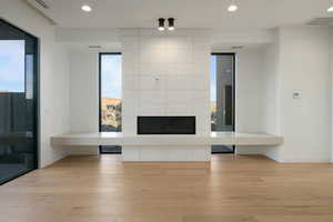 Unfurnished living room with light wood-style floors, a fireplace, visible vents, and recessed lighting