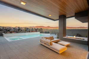 Pool at dusk featuring an outdoor pool, a fire pit, and a patio