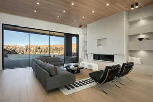 Living room featuring built in features, a glass covered fireplace, wooden ceiling, light wood-type flooring, and a mountain view