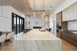 Kitchen with decorative light fixtures, stainless steel gas cooktop, open floor plan, a sink, and modern cabinets