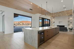 Kitchen featuring beverage cooler, a spacious island, a sink, light wood finished floors, and modern cabinets