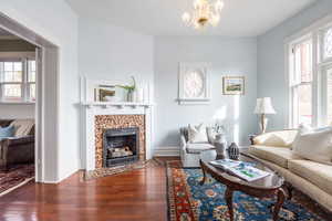 Living area with an inviting chandelier, baseboards, dark wood-type flooring, and a tile fireplace