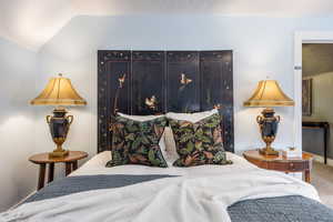 Bedroom featuring carpet and vaulted ceiling