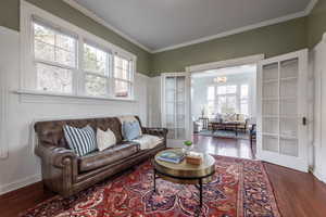 Living area featuring french doors, dark wood finished floors, and crown molding