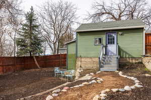 View of outdoor structure with entry steps and a fenced backyard