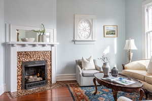 Living area with baseboards, dark wood-type flooring, and a tile fireplace