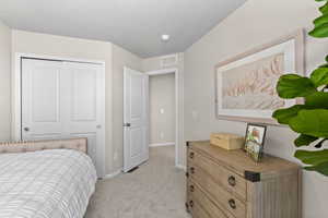 Bedroom with light carpet, a closet, visible vents, and baseboards