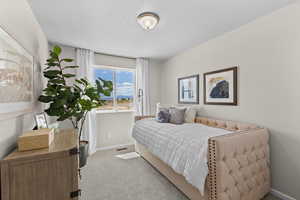 Bedroom with baseboards, light colored carpet, visible vents, and a textured ceiling