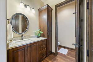 Bathroom with baseboards, vanity, toilet, and wood finished floors