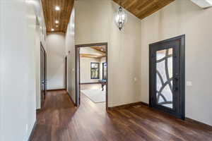 Entryway featuring high vaulted ceiling, dark wood finished floors, wood ceiling, and baseboards