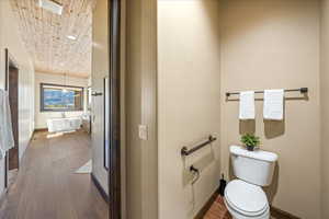 Bathroom with toilet, wood ceiling, a freestanding bath, and wood finished floors