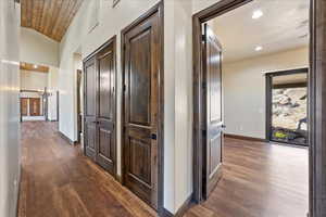 Hall with lofted ceiling, recessed lighting, dark wood-type flooring, a chandelier, and baseboards