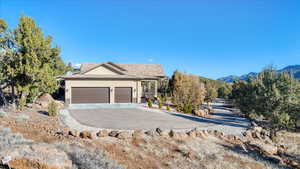 View of front of property with driveway, an attached garage, a mountain view, and stucco siding