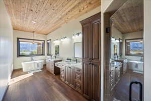 Bathroom with wood ceiling, a freestanding bath, a sink, and wood finished floors