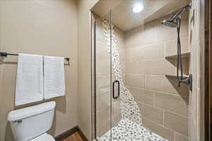 Bathroom featuring toilet, a stall shower, and baseboards