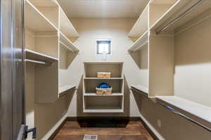 Spacious closet with dark wood-style floors and visible vents