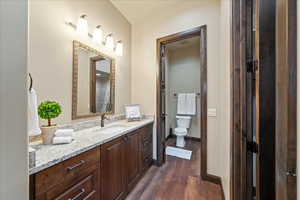 Full bath featuring baseboards, vanity, toilet, and wood finished floors