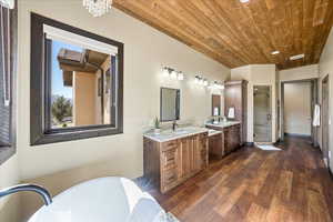 Bathroom featuring wood finished floors, a stall shower, a sink, and wood ceiling