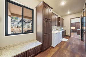 Kitchen with dark wood-type flooring, a wealth of natural light, independent washer and dryer, and light stone countertops