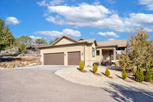 Ranch-style house with a garage, driveway, and stucco siding