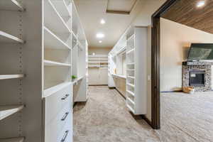 Walk in closet with light carpet and a fireplace