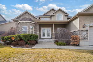 Property entrance featuring stone siding, french doors, and stucco siding