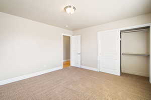 Unfurnished bedroom with carpet floors, baseboards, and a closet